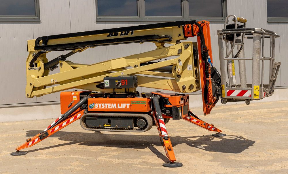 Seitenansicht einer eingefahrenen und robust aufgestellten SYSTEM LIFT Raupenbühne zum Mieten